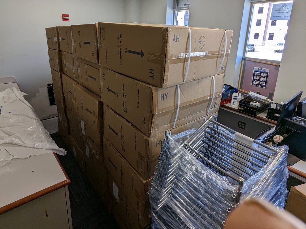 Furniture cartons and task chairs on carts staged inside an office before installation